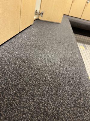 Stinky and probably germ filled carpeted bench in gym locker room.