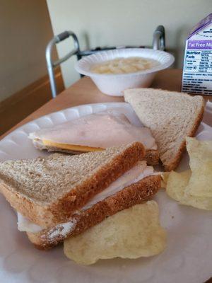 Sunday dinner dry bread turkey sandwhich with chips and bowl of pinapples