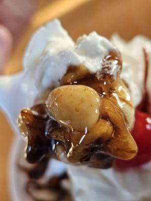 A spoonful of the ice cream sundae with soft vanilla ice cream and chocolate syrup.