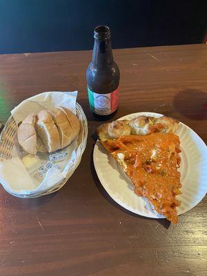 Fresh hot baked bread, a slice of vodka sauce penne pasta pizza, and a vanilla cream soda.