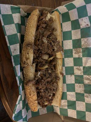 Cheesesteak with fried onions and cooper sharp on a seeded roll