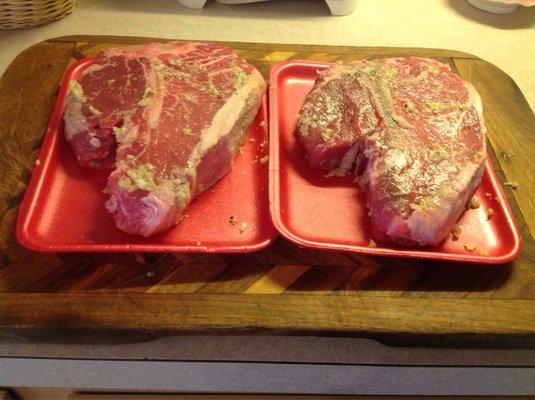 Custom cut Porterhouse steaks covered in garlic and kosher salt, getting ready for the grill.