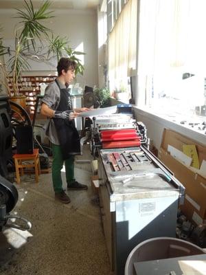 an intern at work on the Vandercook proof press