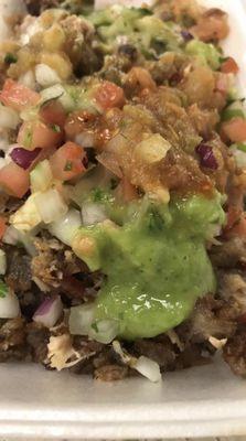 Carnitas and chicharron chopped up and mixed with all the salsas red, green, guacamole with pico de gallo and cilantro and onions