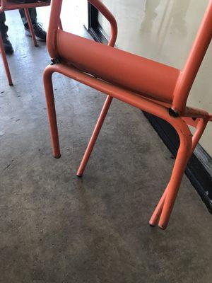 Red chair collapsed back legs against glass wall