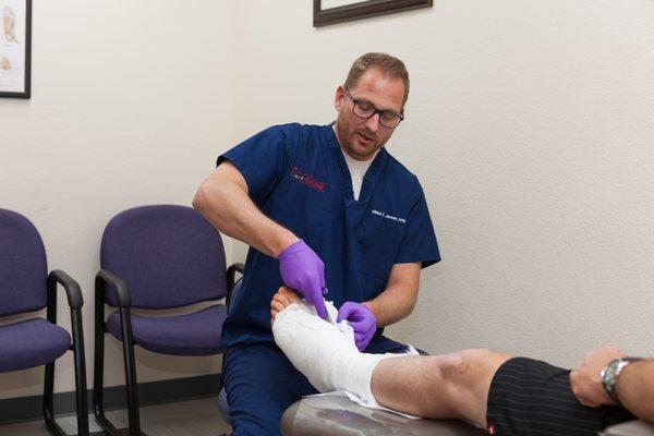 Dr. Mikkel Jarman removing a cast from a patient.