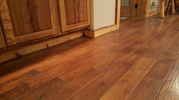 Newly installed hand-scraped hickory flooring with "live-edge" baseboard