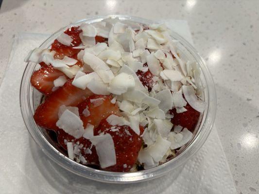 Acai bowl with strawberries, coconut flakes, and granola.