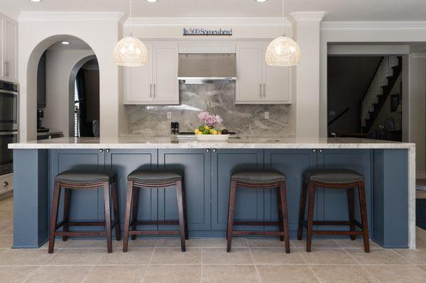 Beautiful Trending Blue cabinets with beverage center, and bar chairs tucked under