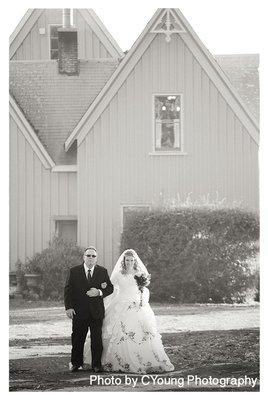 A bride walks down the aisle with the Victorian farmhouse as her backdrop