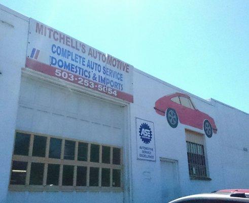 Mitchell's Automotive on Alder & 82nd White building, bay door with customer entrance on right. Red Porsche painted outside