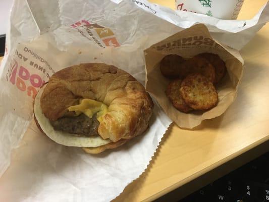 Sausage, egg and cheese on a croissant with hash browns.