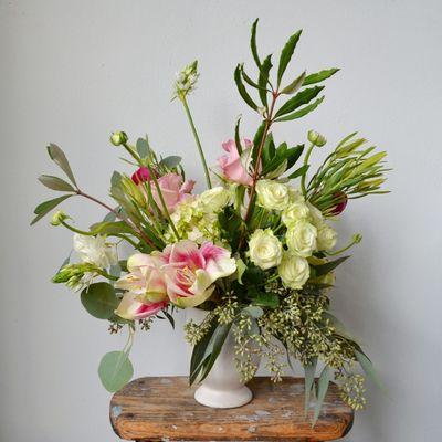 Flower arrangement featuring a mix of whites, greens, and pops of pink