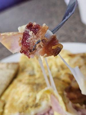 A fork with a piece of bacon from Paul's Omelet.