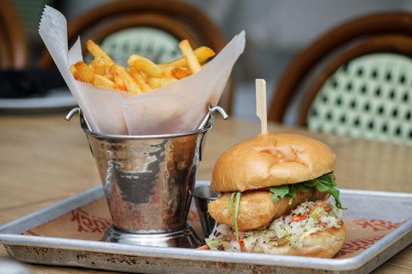 Fresh Catch Fish Sandwhich with Chef's Daily Selection, Fried, Chipotle Aïoli, Mango Crème Fraîche, House Slaw, and Arugula.