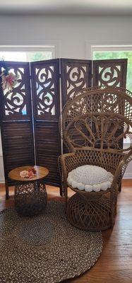 Peacock chair, rug, side table, and room divider backdrop.