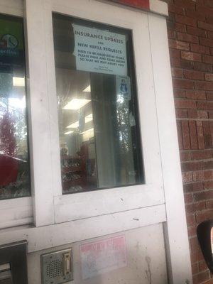 Dirty glass and old tape stuck to pharmacy window.