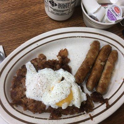 Two poached eggs on homemade corned beef hash with a side of sausage. (Pepper was added by customer)