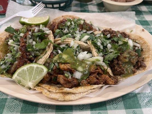 Carne asada tacos + al pastor tacos with their red and green salsa