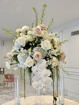 Tall centerpieces with white flowers blush pink roses and phalaenopsis stems falling