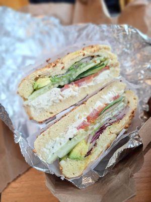 Garlic bagel with garlic cream cheese, tomato, avocado, lettuce, and onions.