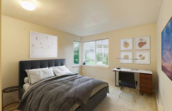 Staged bedroom featuring large windows and an office space.