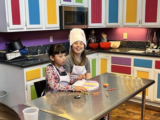 The birthday girl and her friend decorating their chef hat