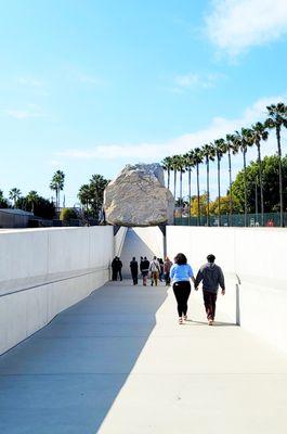 Levitated Mass by Michael Heizer.  Boulder is 21.5 x 21.5 ft, weighing 340 tons.  Approx. 150 million yrs old & designed to last 3,500 yrs.