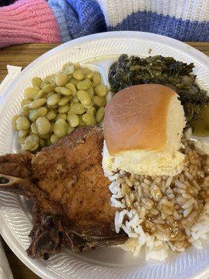 Fried pork chop, rice with gravy, greens, and Lima beans with a roll of