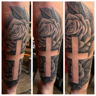 Negative space cross with roses tattoo done by Ed Bell