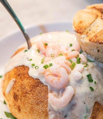 Clam chowder in a bread bowl with shrimp on top