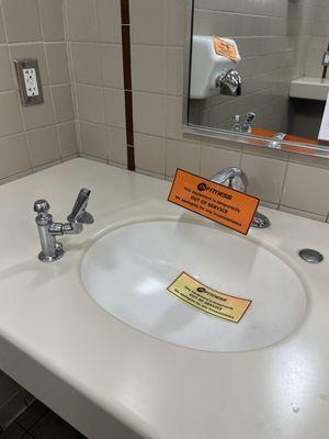 One sink out of service, and one hand dryer out of service (as seen in the mirror reflection).