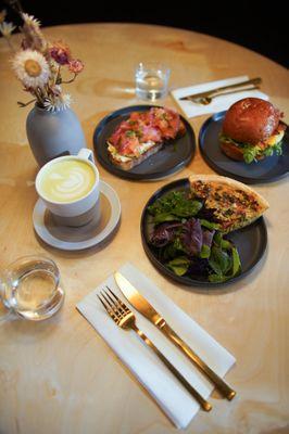 Brunch spread of quiche, salmon toast, breakfast sandwich and latte