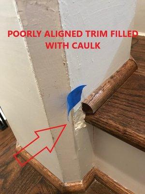 Poorly aligned stair trim filled with caulk throughout