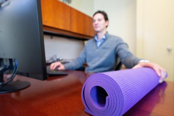 A yoga student closes his computer to get ready for yoga classes in his office. Photo by Dal Perry