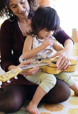 A teacher and child exploring the ukulele.