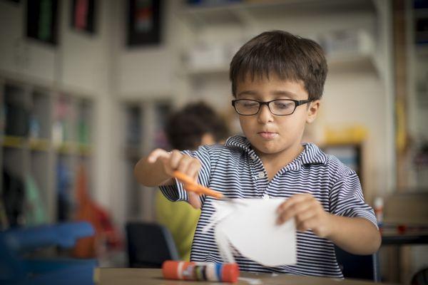 A Pre-Kindergarten student developing fine motor skills, while pairing objects and vocabulary words.