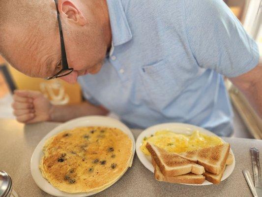 Western omelet with 1 blueberry pancake.  Pancake is as big as his head.