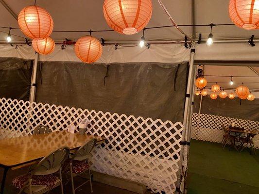 All outdoor seating in a white tent with heat lamps and lanterns