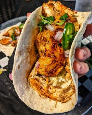 Close-up of a juicy, sweet and spicy Blackened Chicken Tiki Taco with that spicy slaw and seasoning, fresh jalapenos, chili sauce. KILLER.