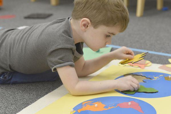 A student putting together the puzzle map of the world.