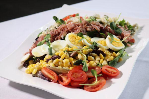 Kentucky Cobb
Baby greens tossed in spiced peach vinaigrette, with egg, country ham, tomato, bleu cheese crumbles, corn, diced peppers