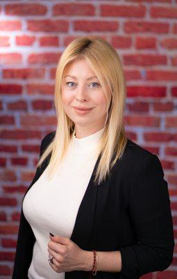 Professional headshot in studio with brick background.