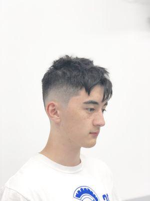 Low skin fade with a textured scissor cut on top.