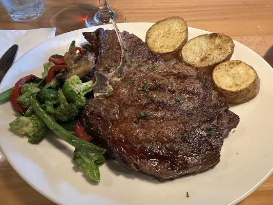 18oz Aged Bone-In Ribeye with mixed vegetables and roasted potatoes.