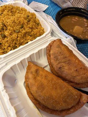 Two beef and cheese empanadas with a side of large yellow rice and beans.