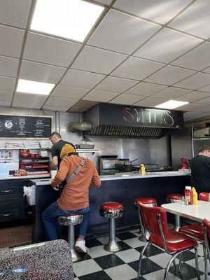 Counter with Chef over fryer- Food Menu on wall