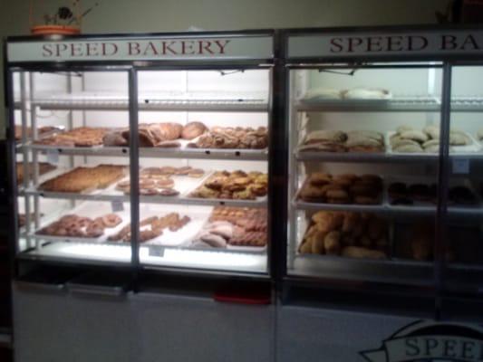 Two cases with breads and pastries with cooler case left of register with FLAN and items requiring fridge.