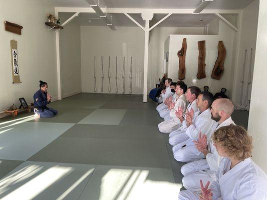 Sitting seiza, a Japanese way of sitting on the mat, while performing wrist warm ups.