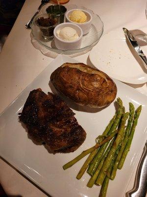 Half of a ribeye with asparagus  baked potato w/toppings